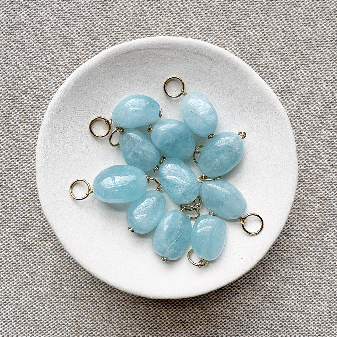 White dish filled with smooth oval aquamarine charms