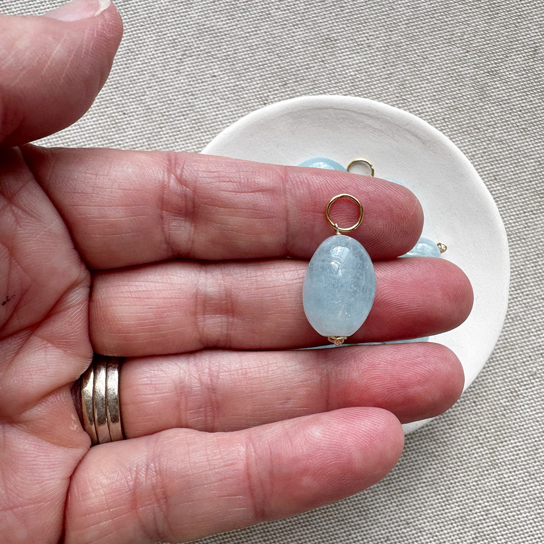 Hand holding a smooth oval aquamarine charm