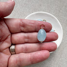 Hand holding a smooth oval aquamarine charm