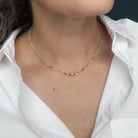 A close-up of a person wearing a delicate white zircon beaded necklace , styled with a white collared shirt.