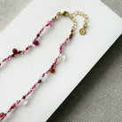 Gemstone necklace in shades of red on a white surface
