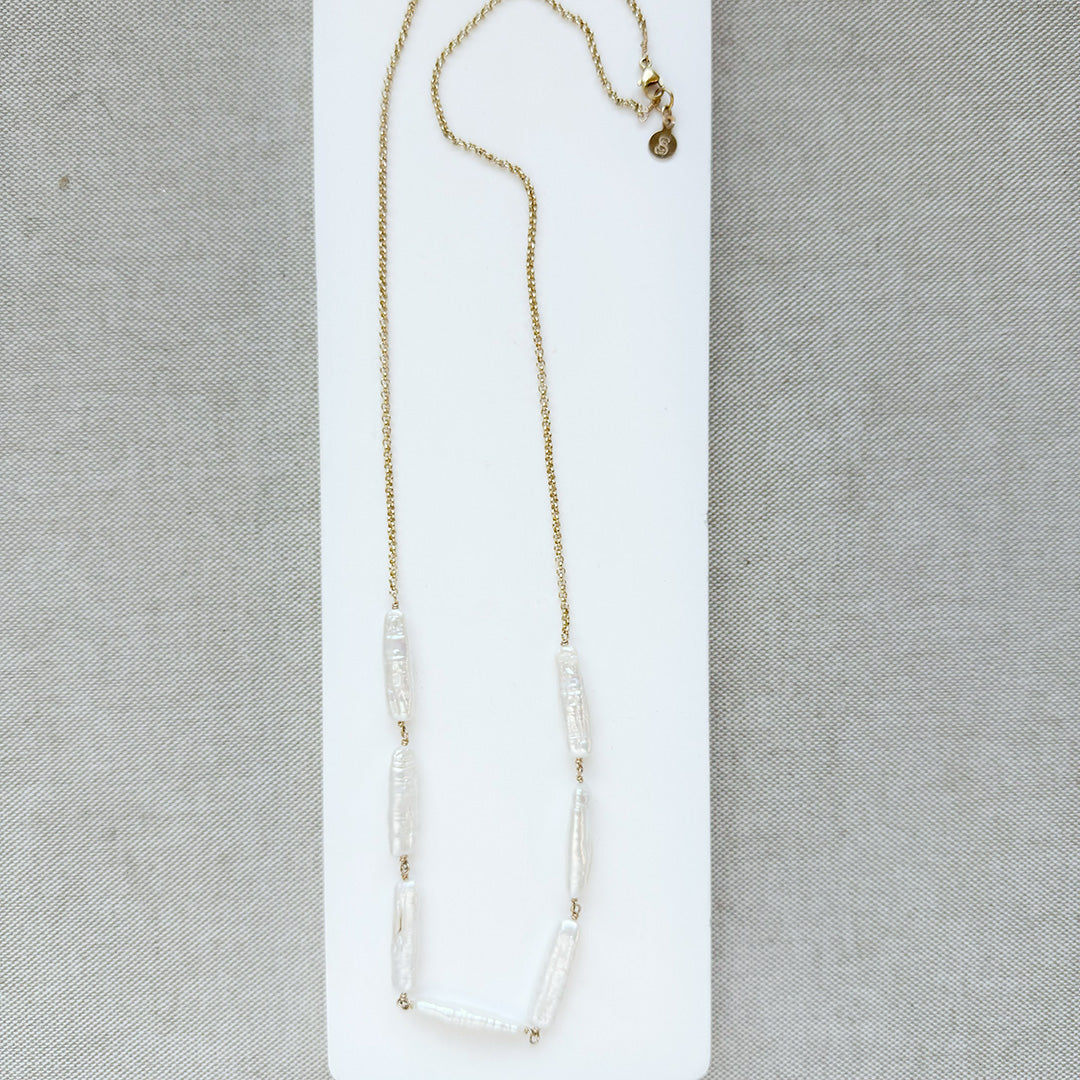 Stick pearl and gold chain necklace on a white background