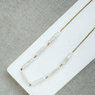 Stick pearl and gold chain necklace on a white background