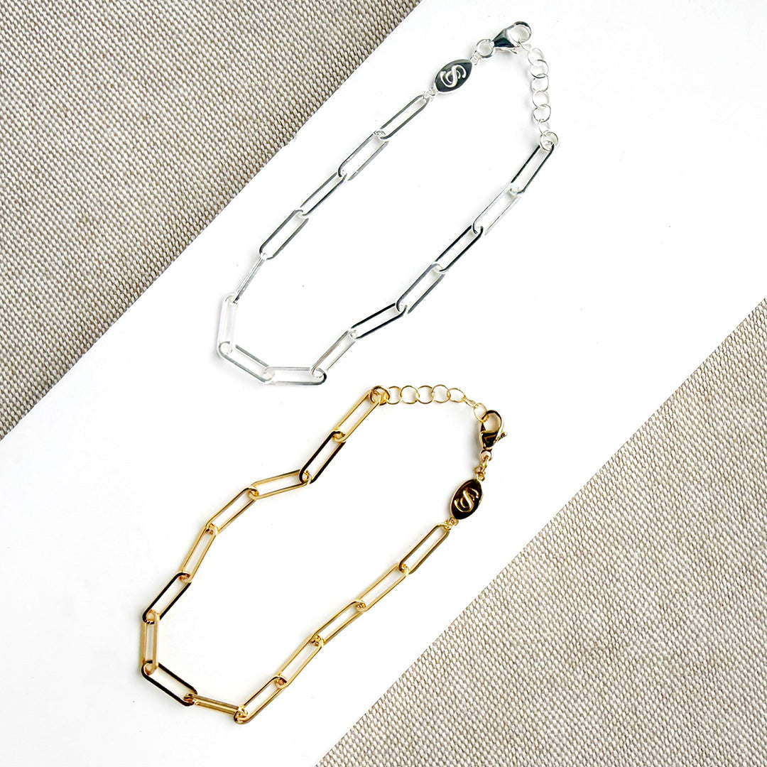 Two gold and silver chain bracelets on a white surface