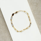 Gold paperclip chain bracelet on a white surface
