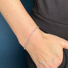 Silver bracelet on a person's wrist against a dark background