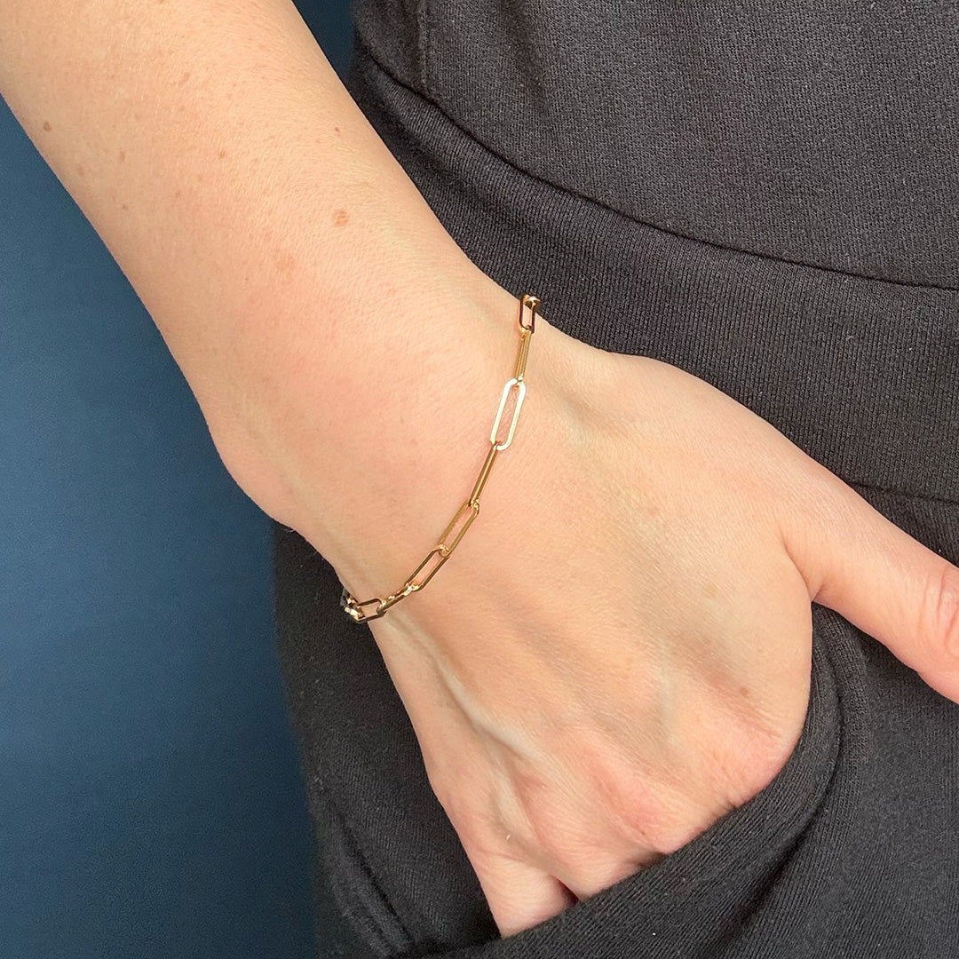 Gold bracelet on a wrist against a dark background