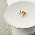Gold and pearl stud earrings on a white stone surface