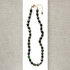 A necklace with faceted Green Tourmaline gemstone beads, on a white surface 