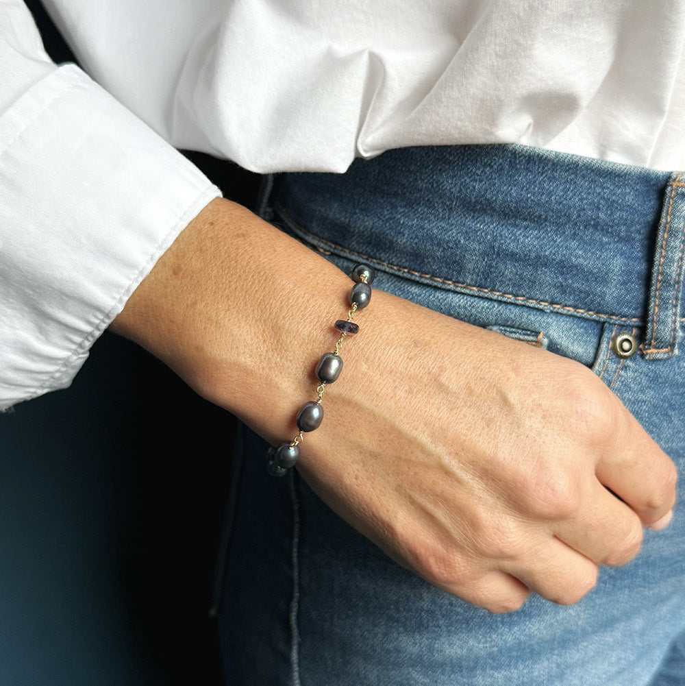 Woman wearing peacock pearl bracelet and jeans