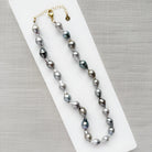 Tahitian pearl necklace on a white surface with a gray background