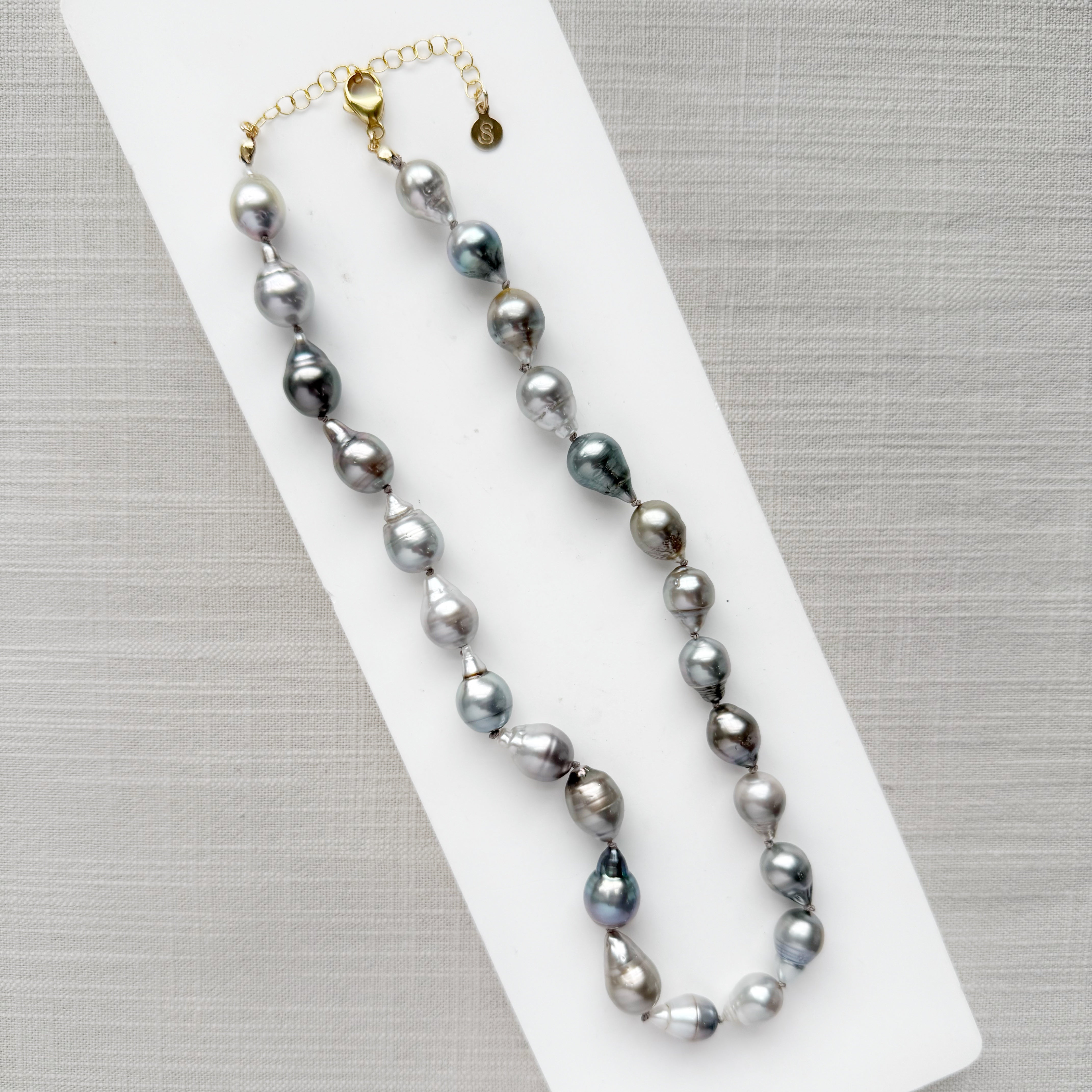 Tahitian pearl necklace on a white surface with a gray background