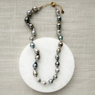 Tahitian pearl necklace on a marble coaster with a textured beige background