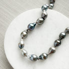 Tahitian pearl necklace on a marble coaster with a textured beige background