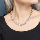 Tahitian pearl necklace worn by a person against a blue background