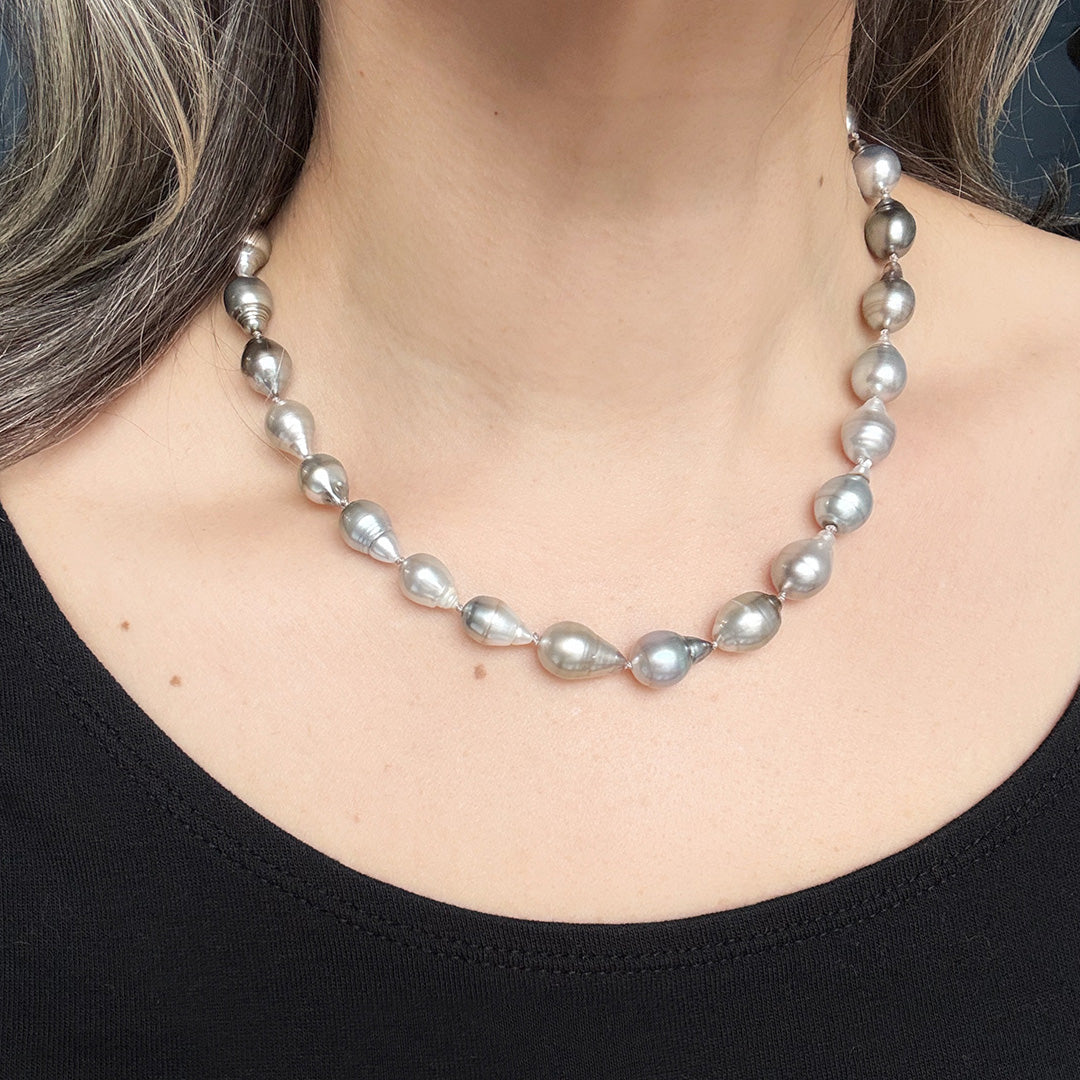 Tahitian pearl necklace worn by a person against a blue background