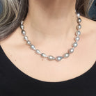 Tahitian pearl necklace worn by a person against a blue background