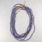 Purple beaded necklace with gold accents on a light gray background
