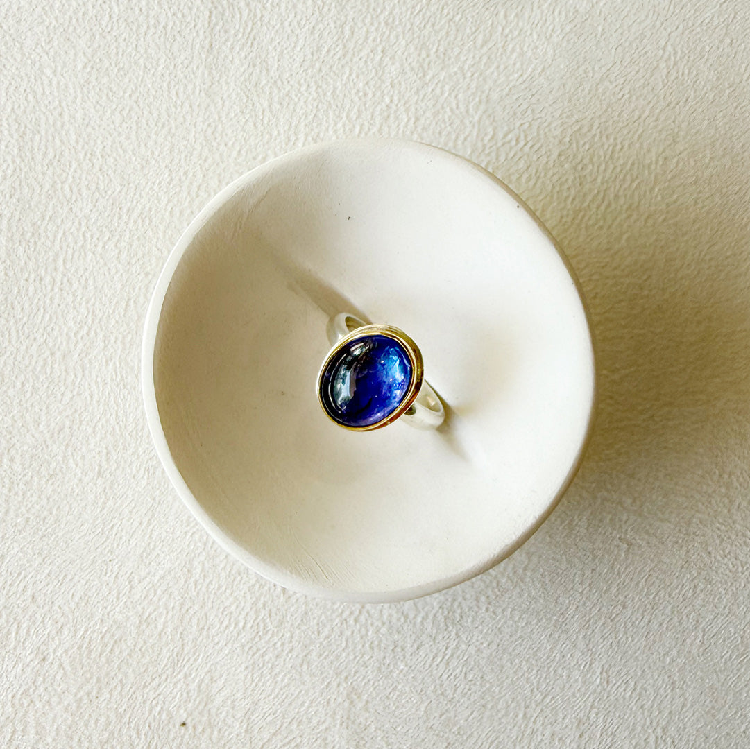 Ring with a purple tanzanite gemstone on a white dish