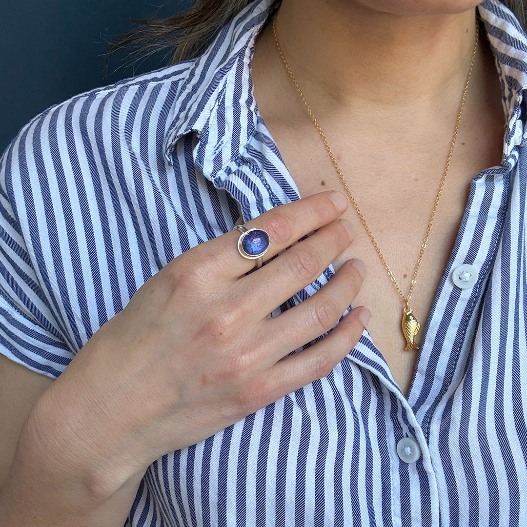 Person wearing a ring with a purple tanzanite gemstone
