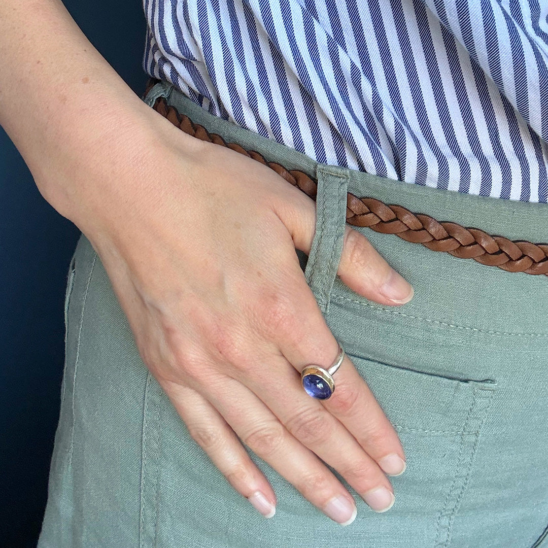 Person wearing a ring with a purple tanzanite gemstone