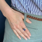 Person wearing a ring with a purple tanzanite gemstone