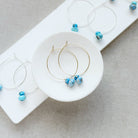 Pairs of hoop earrings with small Golden Hills Turquoise beads, displayed on a white card against a textured gray background.