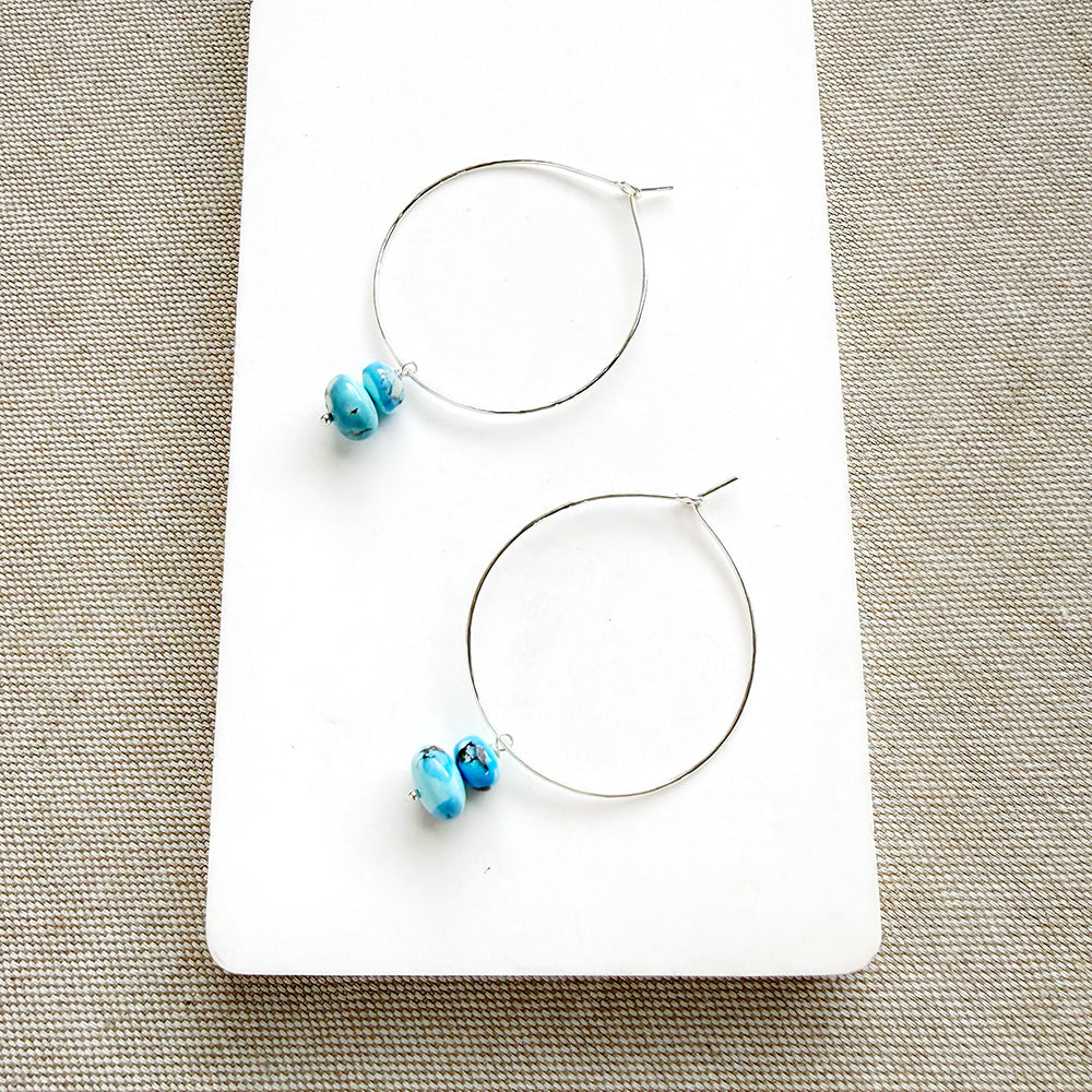 Pair of hoop earrings with small Golden Hills Turquoise beads, displayed on a white card against a textured gray background.