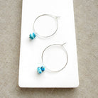 Pair of hoop earrings with small Golden Hills Turquoise beads, displayed on a white card against a textured gray background.
