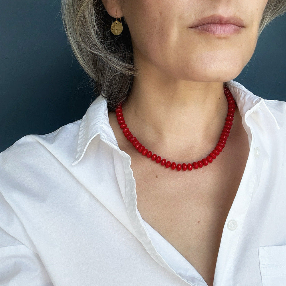 Woman wearing red coral knotted necklace and a white shirt