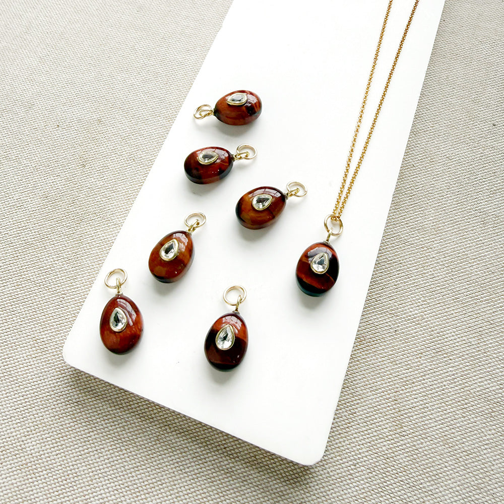 Tiger Eye charm with inset cz stone in a white dish