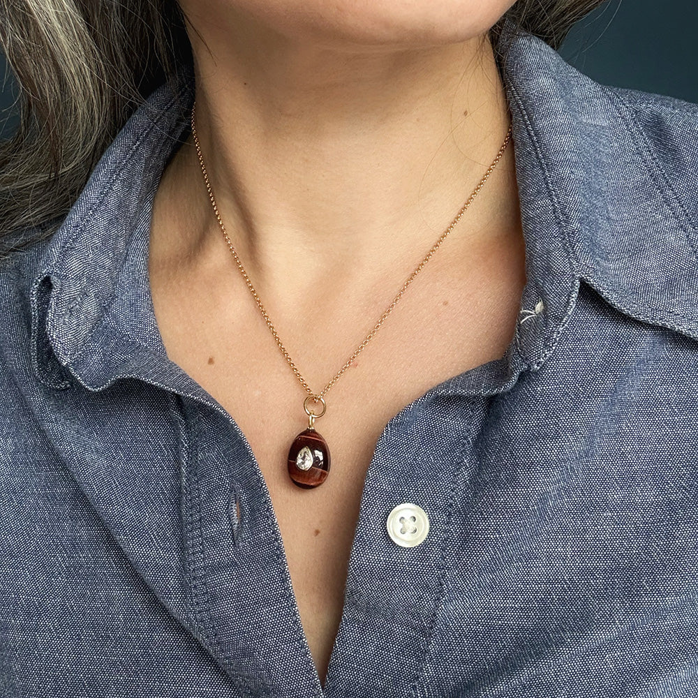 Woman wearing tiger Eye charm with inset cz stone on a gold chain