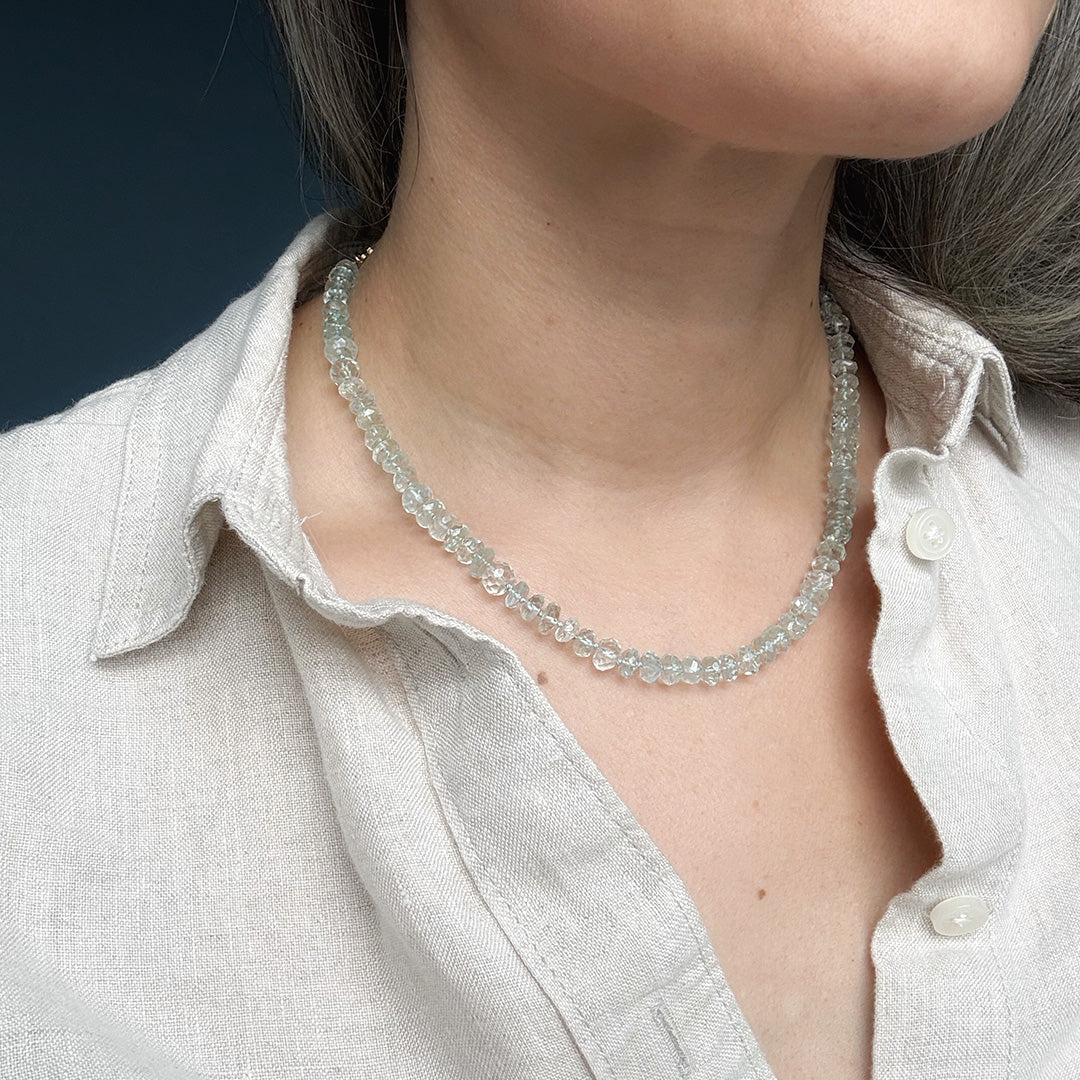 Close up of woman wearing blue topaz necklace on a dark blue background