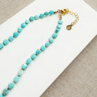 Turquoise beaded necklace with gold clasp on a white card