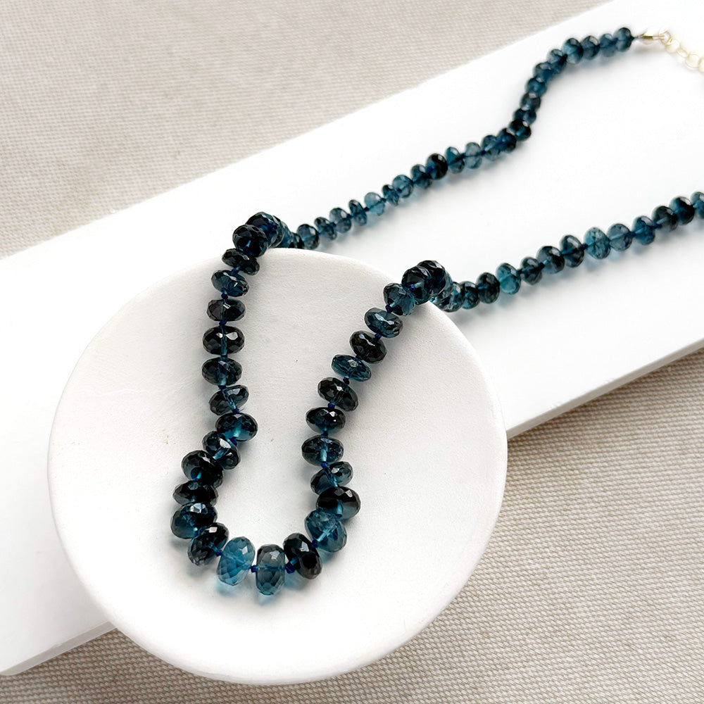 London Blue knotted necklace in a white dish