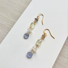 Pair of gold earrings with multicolored beads on a white surface.