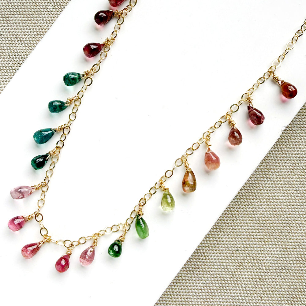 Gold necklace with dangling teardrop-shaped Watermelon Tourmaline gemstones in pink, green, and teal on a white background