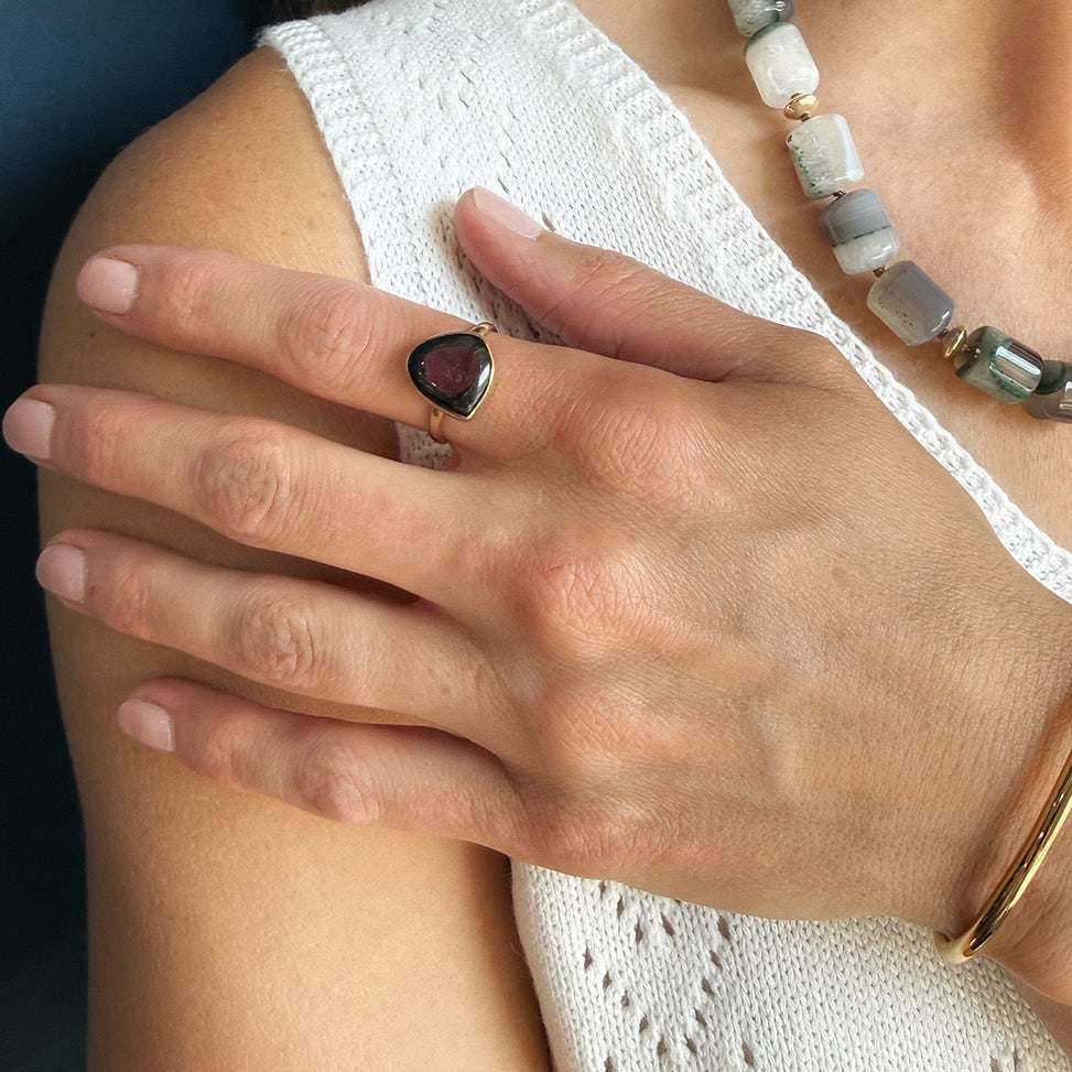 Close up of woman wearing a watermelon tourmaline one of a kind ring in a white dish