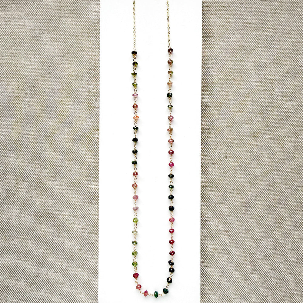A gemstone necklace with small faceted Watermelon Tourmaline beads in pink, green and blush, on a white background.