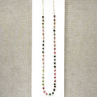 A gemstone necklace with small faceted Watermelon Tourmaline beads in pink, green and blush, on a white background.