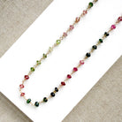A gemstone necklace with small faceted Watermelon Tourmaline beads in pink, green and blush, on a white background.