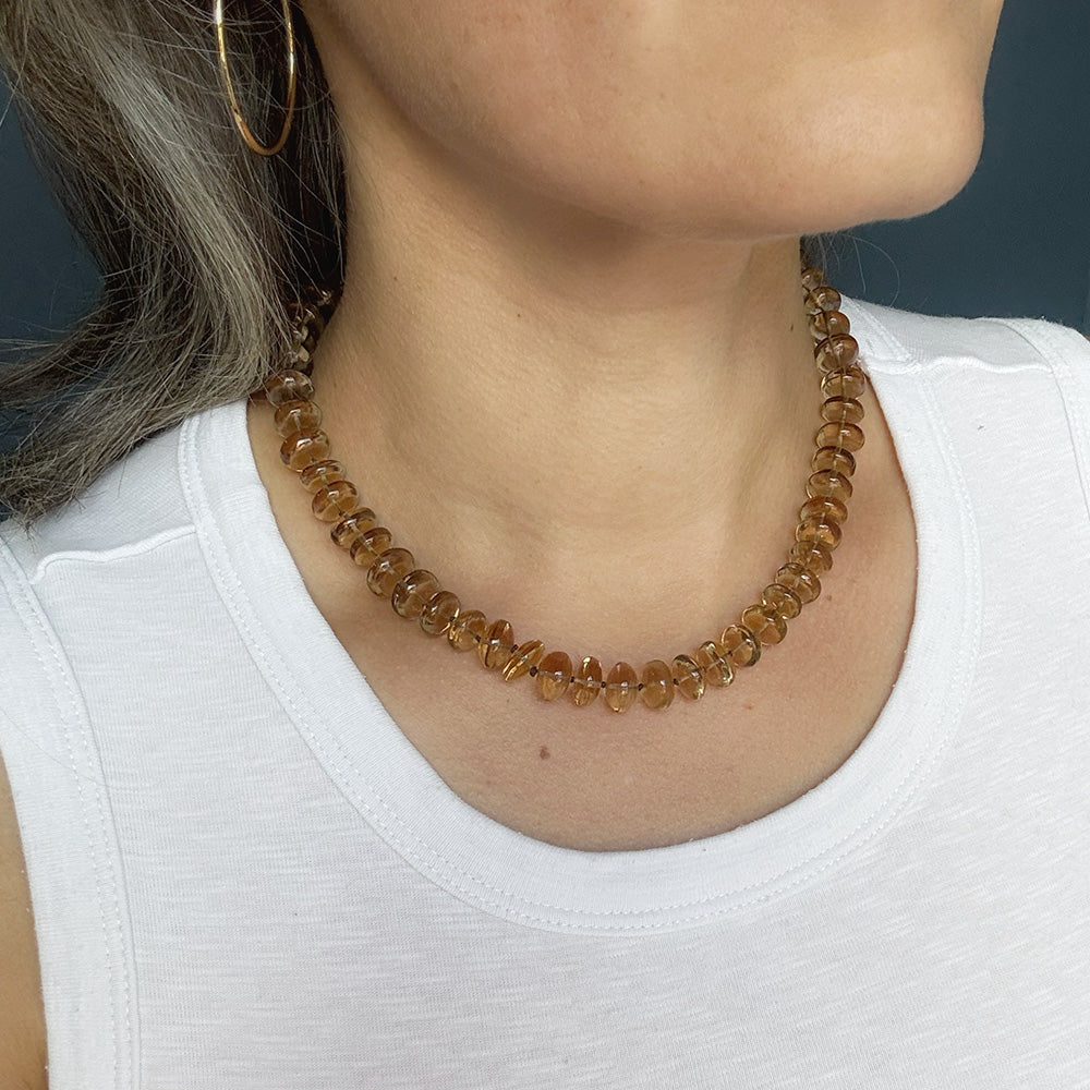 Woman wearing whiskey quartz knotted necklace and a white tank top