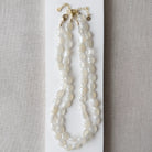 White chalcedony knotted necklace on a white card with a gray background