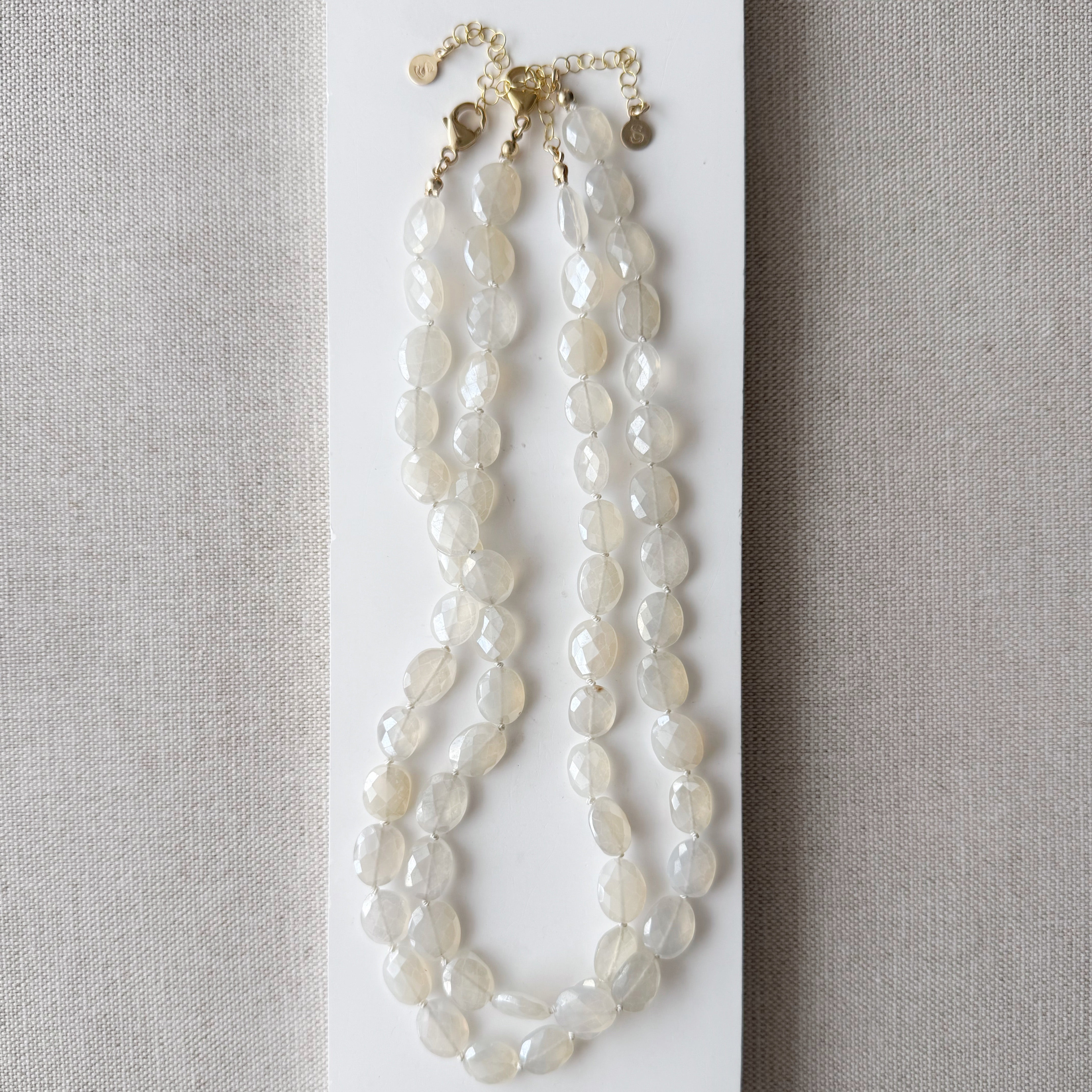 White chalcedony knotted necklace on a white card with a gray background