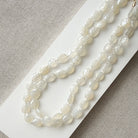 White chalcedony knotted necklace on a white card with a gray background