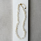 White chalcedony knotted necklace on a white card with a gray background