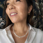 Woman wearing a white shirt and white chalcedony necklace with a floral background