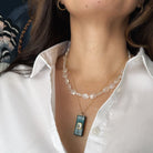 Person wearing a white shirt with a white chalcedony necklace and a rectangular pendant.