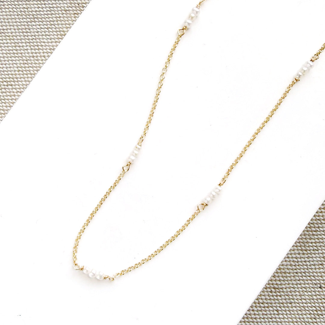Delicate gold necklace with pearls on a textured surface