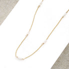 Delicate gold necklace with pearls on a textured surface